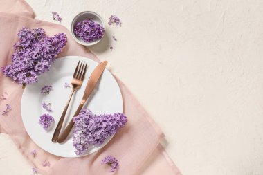 Beyaz arka planda leylak çiçekleri olan güzel bir masa.