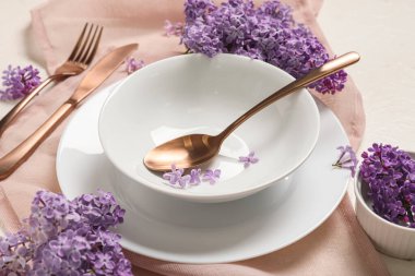 Beyaz arka planda leylak çiçekleri olan güzel masa ayarları, yakın plan.