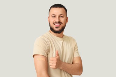 Uygulamalı tıbbi yaması olan genç adam arka planda baş parmağını kaldırıyor. Dokunulmazlık kavramı