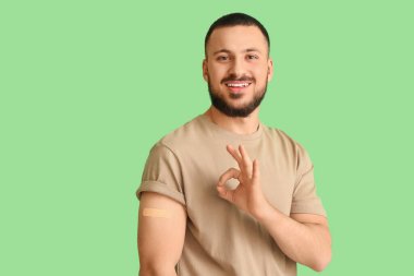 Uygulamalı tıbbi yaması olan genç adam yeşil arka planda iyi görünüyor. Dokunulmazlık kavramı