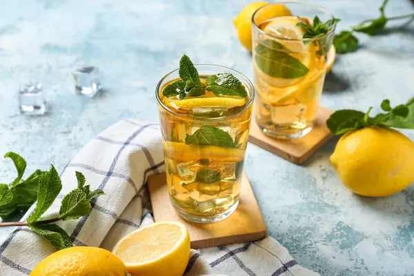Mavi arka planda nane ve turunçgil meyveli limonlu buzlu çay, yakın plan.
