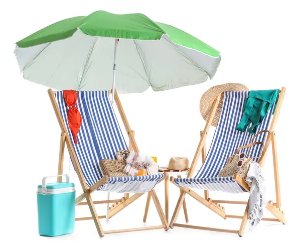 Yeşil plaj şemsiyeli çizgili güverte sandalyeleri ve beyaz arka planda izole edilmiş seyahat aksesuarları.