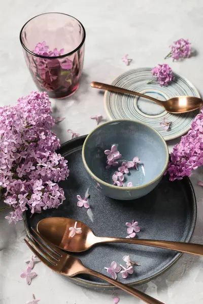 Gri arkaplanda leylak çiçekleri olan güzel masa ayarı, yakın plan.