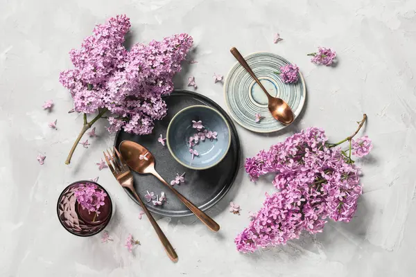 Gri arkaplanda leylak çiçekleri olan güzel bir masa.