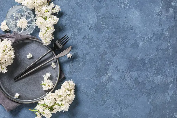 Mavi arka planda beyaz leylak çiçekleri olan güzel bir masa.