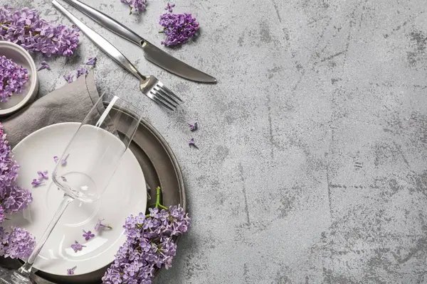 Gri arkaplanda leylak çiçekleri olan güzel bir masa.