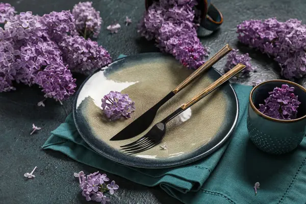 Koyu arkaplanda leylak çiçekleri olan güzel masa ayarı, yakın plan.