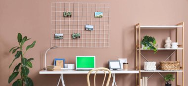 Laptop, raf ünitesi ve odasındaki kahverengi duvarın yanındaki tahtalı modern işyeri.