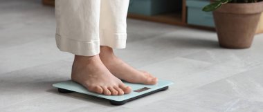 Evde terazinin üzerinde duran genç bir kadın. Kilo verme konsepti