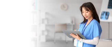 Klinikte panoya yazı yazan Asyalı kadın doktor.