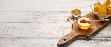 Bal kaseleri ve beyaz ahşap arka planda taraklar