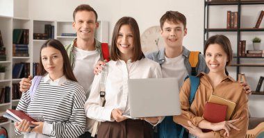 Kütüphanede dizüstü bilgisayarı ve kitapları olan bir grup öğrenci.