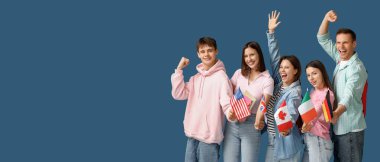 Farklı ülkelerin bayraklarına sahip mutlu öğrencilerden oluşan bir grup mavi arkaplanda metin için yer var