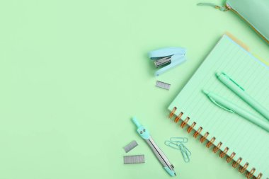 Yeşil arka planda farklı kırtasiye malzemesi içeren kompozisyon