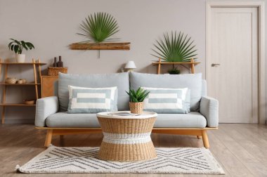 Oturma odasında kanepe, masa ve palmiye yaprakları var.