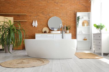 Küveti, raf ünitesi, aynası ve lavabosu olan şık bir banyo.