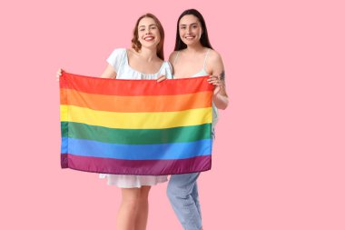 Pembe arka planda LGBT bayrağı olan güzel bir lezbiyen çift.