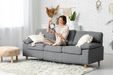 Evde kanepede oturan rüya kapanı olan genç bir kadın.