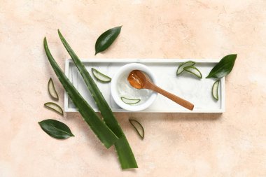 Bir kase aloe vera jeli ve bej arkaplanda yapraklar