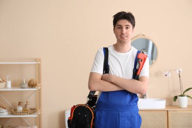 Banyoda boru anahtarı ve alet çantası olan bir erkek tesisatçı.