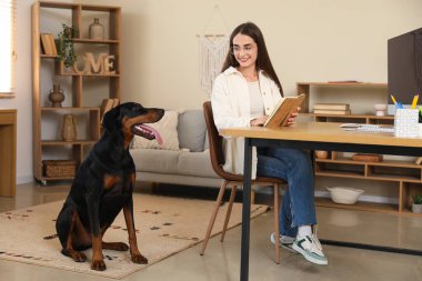 Sevimli Doberman köpeği ve güzel, mutlu, genç bir kadın iş yerinde kitabı olan.