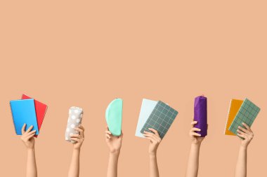 Bej arka planda farklı okul malzemelerine sahip kadın eller.