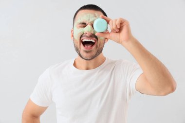 Yüzünde kozmetik balon maskesi ve gri arka planda kavanozu olan yakışıklı genç adam.