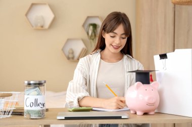 Evde deftere yazı yazan bir kız öğrenci. Eğitim tasarruf kavramı