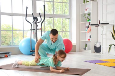 Rehabilitasyon merkezinde küçük kızla çalışan erkek fizyoterapist.