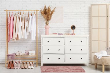 Modern giyinme odasının şık iç mekanı kadın kıyafetleri ve otlarla dolu.