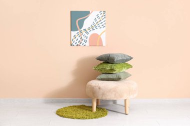 Yastıklı puf ve odadaki bej duvarda resim