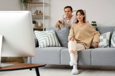 Genç çift evde kanepede televizyon izlerken