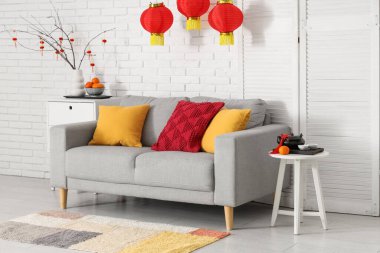 Çin Yeni Yılı için dekore edilmiş oturma odasının içi kanepe, masa ve katlanır ekran ile süslenmiş.