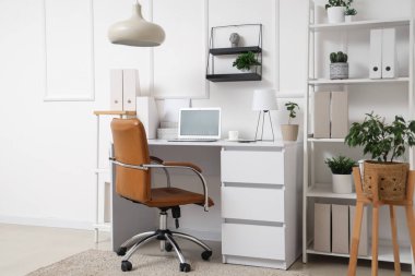 Çalışma yeri, modern laptop ve rahat koltuğu olan şık bir ofis.