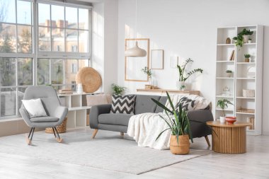 Oturma odasının içinde kanepe, sallanan koltuk ve bitkiler var.