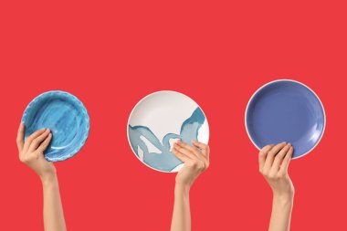 Kırmızı arka planda farklı plakalar tutan kadın eller