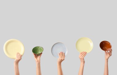 Beyaz arka planda tabakları ve kaseleri olan kadın elleri