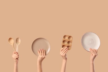 Tabaklı kadın elleri, tahta yumurta tutacağı ve bej arka planda kaşıklar.