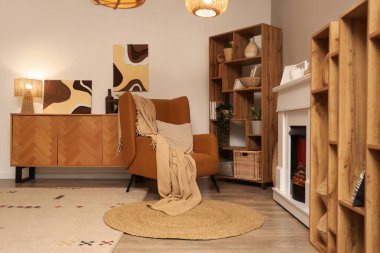 Oturma odasının içinde şömine, koltuk ve raf üniteleri var.