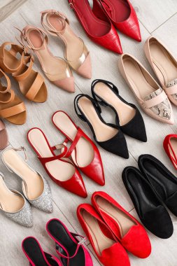 Açık ahşap zeminde farklı kadın ayakkabıları, üst manzara.