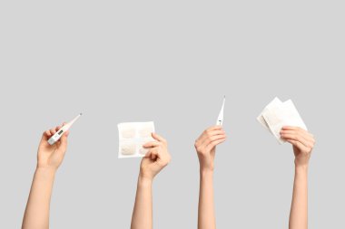 Hardal alçılı kadın elleri ve gri arka planda termometreler.