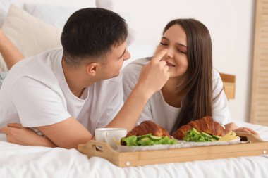 Ayçöreği olan genç bir çift yatak odasında kahvaltı yapıyor.