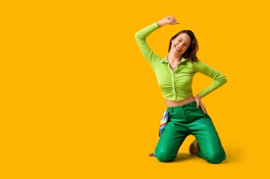 Sarı arka planda dans eden güzel genç bir kadın