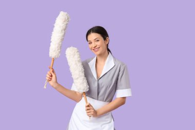 Mor arka planda pp-toz bezleri olan güzel bir oda hizmetçisi.