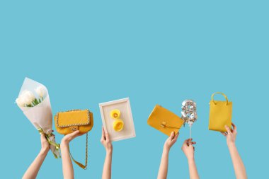 Mavi arka planda el çantaları, çiçekler ve balonla kartpostal tutan bir kadın. Uluslararası Kadınlar Günü için Alışveriş