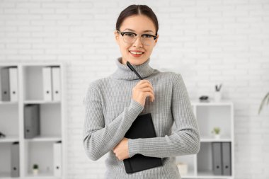 Not defteri ve kalemi olan genç Asyalı iş kadını.