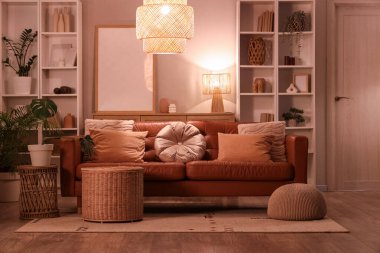 Modern oturma odasının içinde kahverengi kanepe, raf üniteleri ve akşam lambaları var.