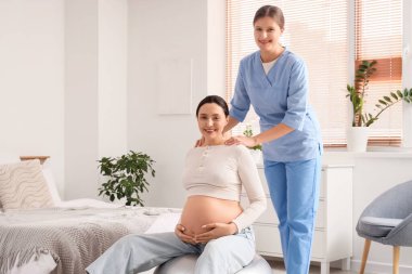 Hamile bir kadınla birlikte yatak odasında fitbol antrenmanı yapan genç Doula.