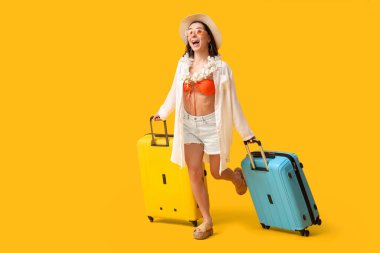 Sarı arka planda koşan valizli genç bayan turist.