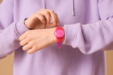 Bej arka planda pembe kol saati olan kadın, yakın plan.